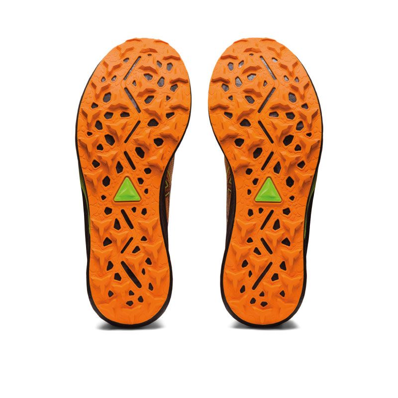 Zapatilla de trail running ASICS Fuji Speed 2 de color naranja con detalles en verde, en acción, con un corredor que la lleva puesta y corre por un sendero de montaña, mostrando la velocidad, la comodidad y la estabilidad que ofrece la zapatilla en los terrenos más exigentes.